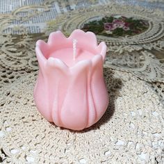 a pink candle sitting on top of a doily