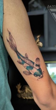 a woman's arm with a fish tattoo on it