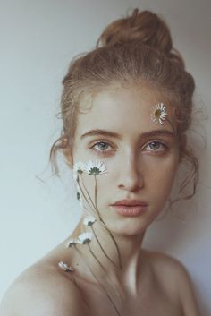 a woman with flowers in her hair and nose piercings on her head, looking at the camera