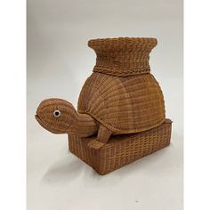 a wicker turtle sitting on top of a wooden basket in the shape of a vase