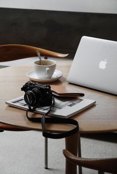 an apple laptop computer sitting on top of a wooden table next to a cup of coffee