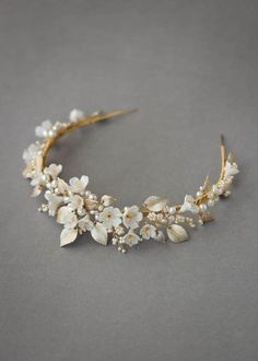 a headband with white flowers and pearls on the side, sitting on a gray surface