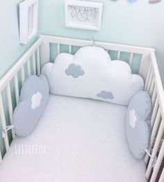 a baby crib with a cloud shaped pillow in the middle and pictures on the wall