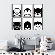 four black and white superhero wall art prints in a child's room with toys on the floor