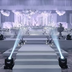 an aisle decorated with white flowers and candles for a wedding or event venue, lit by blue lights