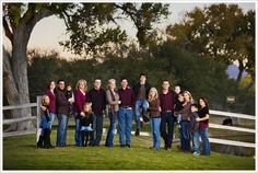 a group of people standing next to each other in front of a fence and trees