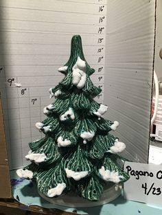 a ceramic christmas tree sitting on top of a table next to a ruler and other items