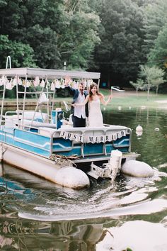 a man and woman standing on the back of a blue boat in a body of water