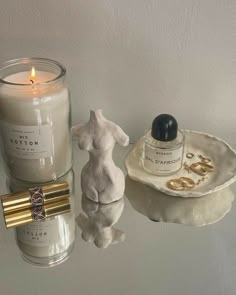 a candle and some other items sitting on a table next to each other in front of a white wall