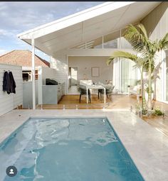 an empty pool in front of a house with a patio and dining table next to it