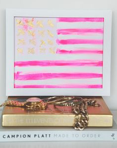 a pink and gold american flag is on top of two books with chains attached to it