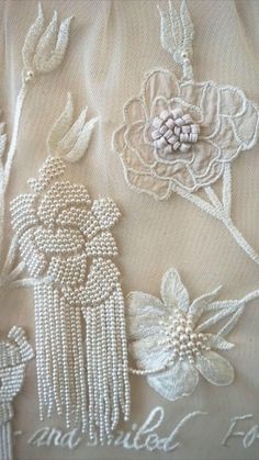 an embroidered fabric with flowers and pearls on the bottom, along with words written in cursive writing