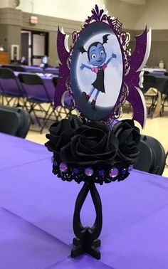 a purple table topped with black roses and an image of a cartoon character on it