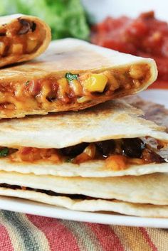 three tortillas on a plate with salsa and lettuce in the background