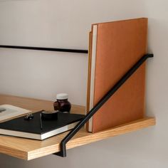 an open book sitting on top of a wooden shelf next to a cup and pen