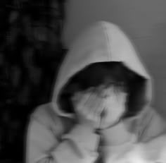 a blurry image of a person covering their face with his hands and looking at the camera