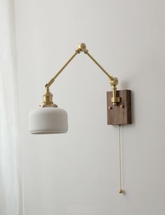 a wall light with a white shade hanging from it's side