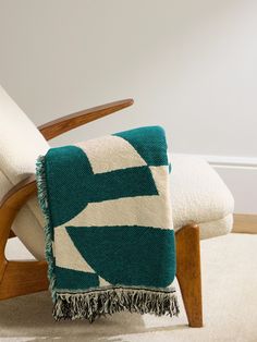 a green and white blanket sitting on top of a wooden chair next to a wall