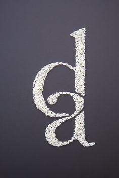 the letter g is made out of rice on a black surface with white writing underneath it