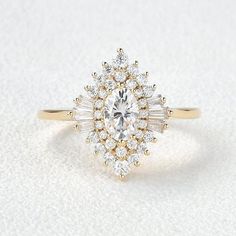 a yellow gold ring with an oval cut diamond surrounded by smaller round diamonds