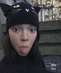 a woman sticking her tongue out and wearing a cat hat