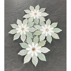 some white flowers on a black surface with green leaves in the middle and brown centers