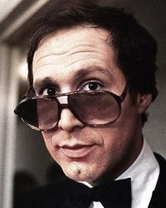 a man in a tuxedo and bow tie with sunglasses on his face looking at the camera