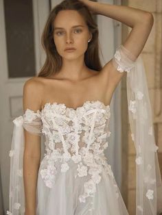 a woman in a white wedding dress with flowers on the skirt and veil over her head