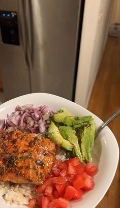 a white plate topped with meat, rice and veggies next to a refrigerator