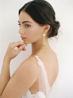 a woman in a white dress is posing with her hand on her chin and looking off to the side