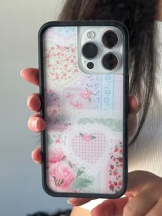 a woman holding up her phone case with flowers and hearts on it in front of her face