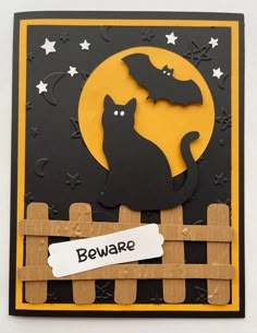 a halloween card with a cat and bat on the fence that says beware,