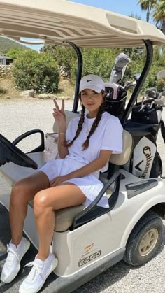 a woman sitting in a golf cart giving the peace sign