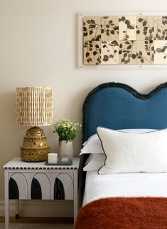 a bedroom with a blue headboard, white bedding and decorative artwork on the wall