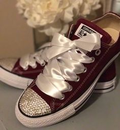 a pair of red and white sneakers with bows on the side, next to a flower