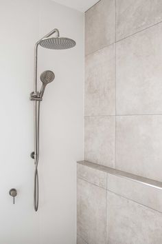 a shower head and hand held shower faucet in a white bathroom with tile walls