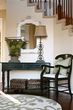 a room with a chair, table and mirror on the wall next to a stair case