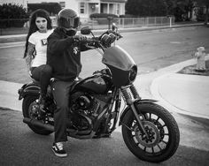 black and white photograph of two people sitting on a motorcycle