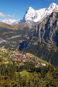 the mountains are covered in snow and green grass, with small village nestled on each side