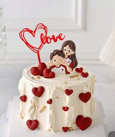 a white cake with red hearts on it and a love sign in the top corner