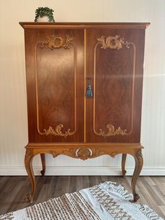 an old wooden armoire sitting on top of a hard wood floor next to a rug