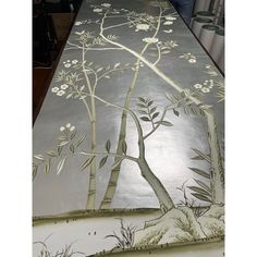 a long table covered with an artistic painting on it's sides and trees in the middle