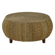 a round woven ottoman sitting on top of a wooden table