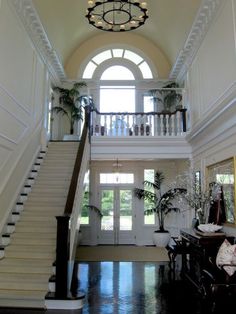 the stairs in this house are white and have black railings on each side, along with a chandelier above them