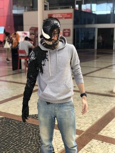 a man wearing a mask and jeans stands on a skateboard in an indoor area