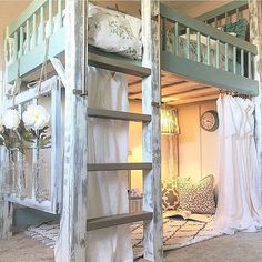 a bunk bed in a room with curtains on the walls and stairs to the second floor