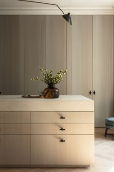 a vase with some flowers on top of a counter in a room that has wood paneling