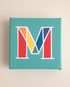 the letter m is made up of multicolored letters on a light blue background