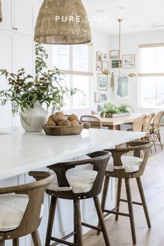 a kitchen with white counter tops and stools next to a large island topped with plants