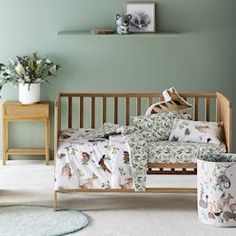 a baby bed with animals on it in a green room next to two planters